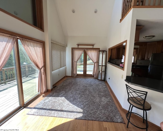 living room with light wood-type flooring, high vaulted ceiling, and french doors