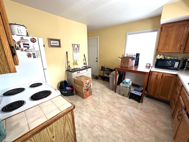 kitchen featuring white fridge, stove, and light tile floors