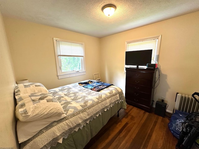 bedroom featuring a textured ceiling, dark hardwood / wood-style floors, and radiator heating unit