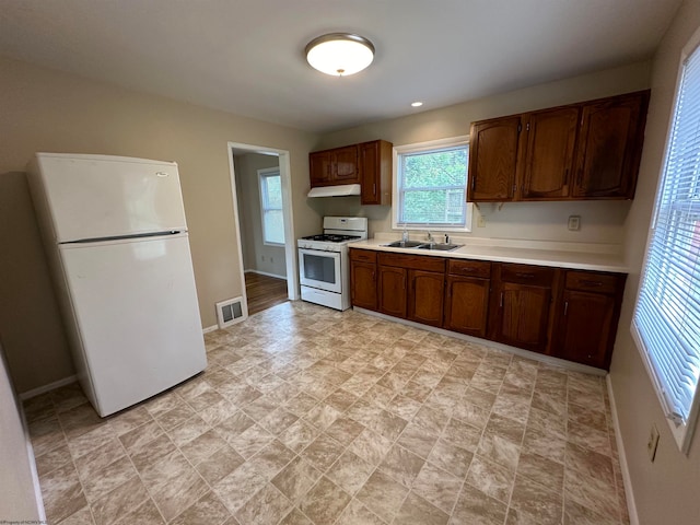 kitchen with under cabinet range hood, white appliances, a sink, visible vents, and light countertops