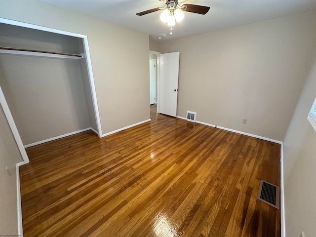 unfurnished bedroom featuring a closet, wood finished floors, visible vents, and baseboards