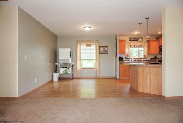 kitchen featuring a healthy amount of sunlight, light hardwood / wood-style flooring, and pendant lighting