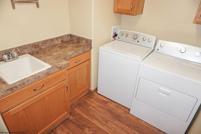 laundry room with washing machine and clothes dryer, hookup for a washing machine, dark hardwood / wood-style flooring, sink, and cabinets