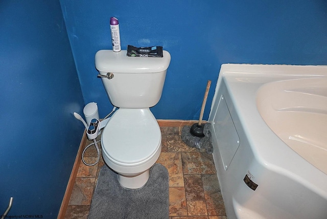 bathroom featuring washer / dryer, tile flooring, and toilet