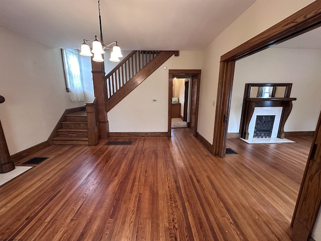 unfurnished living room featuring wood-type flooring and an inviting chandelier