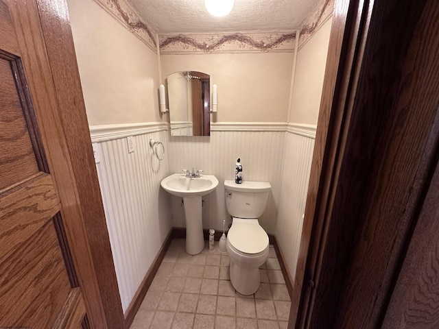 bathroom featuring a textured ceiling, toilet, and sink