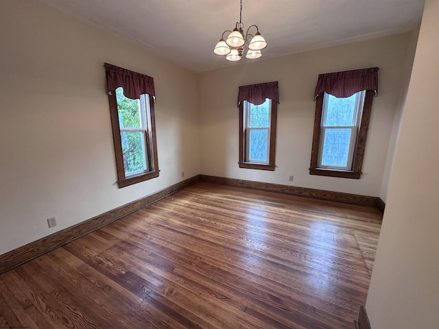 spare room featuring hardwood / wood-style floors and an inviting chandelier