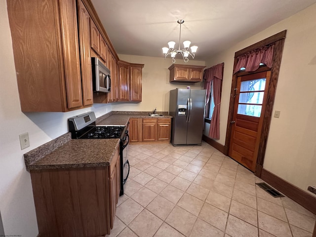 kitchen with stainless steel appliances, sink, light tile patterned floors, a notable chandelier, and hanging light fixtures