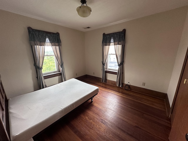 bedroom with multiple windows and dark hardwood / wood-style flooring