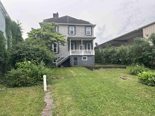 rear view of house featuring a lawn and a porch