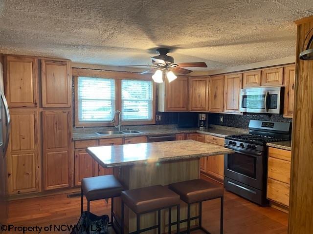 kitchen featuring sink, a breakfast bar area, a center island, dark hardwood / wood-style flooring, and stainless steel appliances