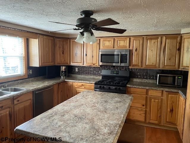 kitchen with ceiling fan, a center island, a textured ceiling, and black appliances