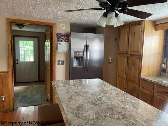 kitchen with ceiling fan, stainless steel fridge with ice dispenser, a textured ceiling, and light wood-type flooring