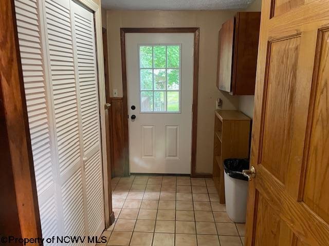 doorway to outside featuring light tile patterned floors and a textured ceiling