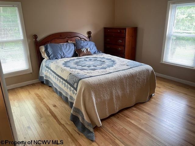 bedroom with multiple windows and light wood-type flooring