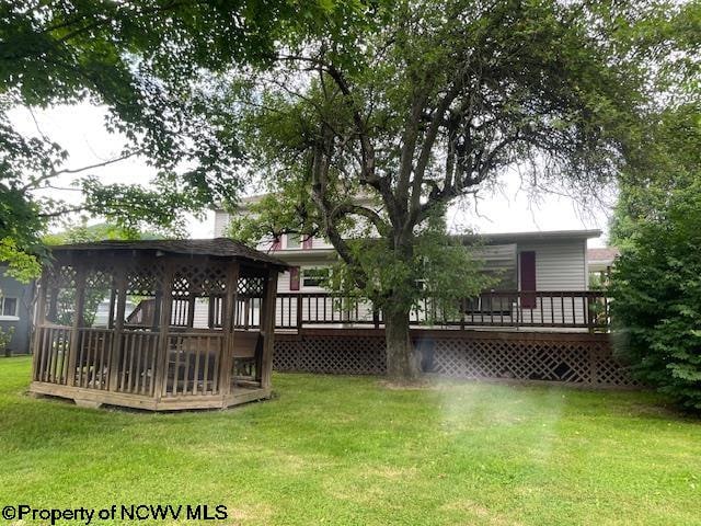 rear view of house with a wooden deck, a yard, and a gazebo