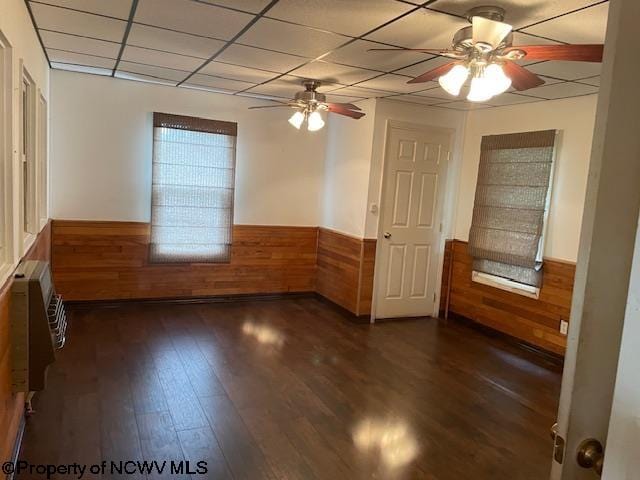 spare room with dark hardwood / wood-style flooring, a paneled ceiling, a wall unit AC, and ceiling fan