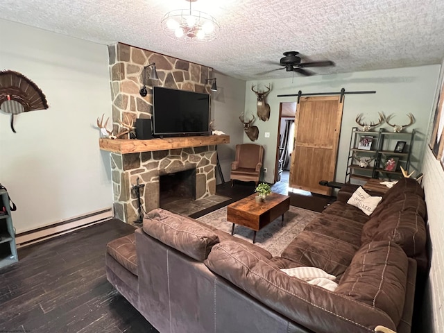 living room featuring a baseboard heating unit, a textured ceiling, a barn door, a stone fireplace, and ceiling fan