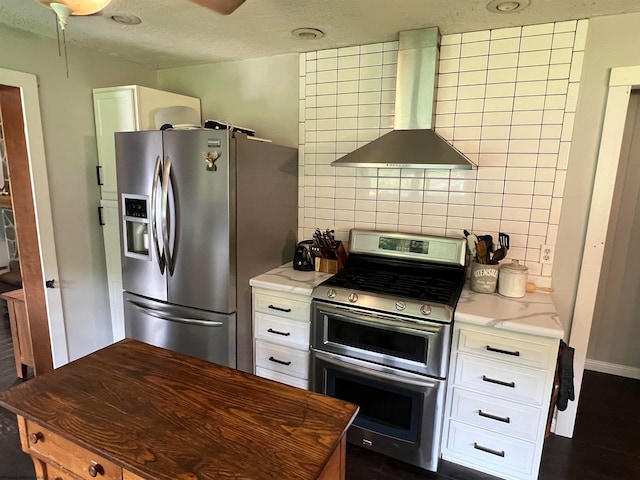 kitchen with appliances with stainless steel finishes, white cabinetry, and wall chimney range hood