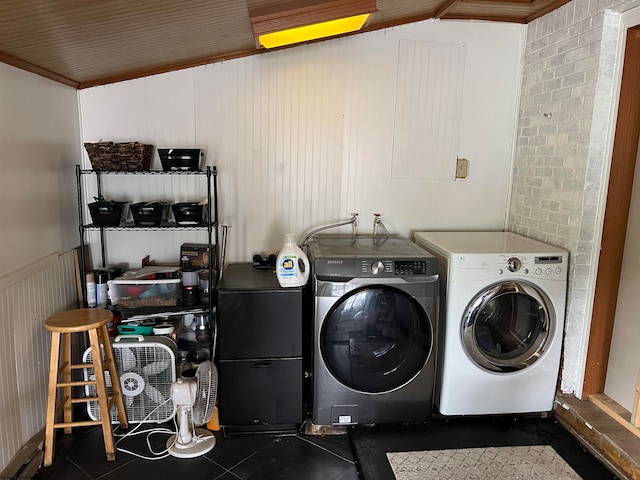 laundry room featuring tile floors, brick wall, and washer and clothes dryer