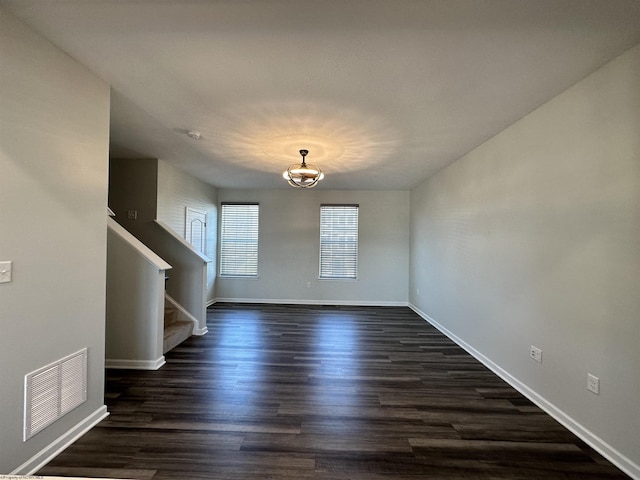 spare room with dark hardwood / wood-style flooring and a notable chandelier