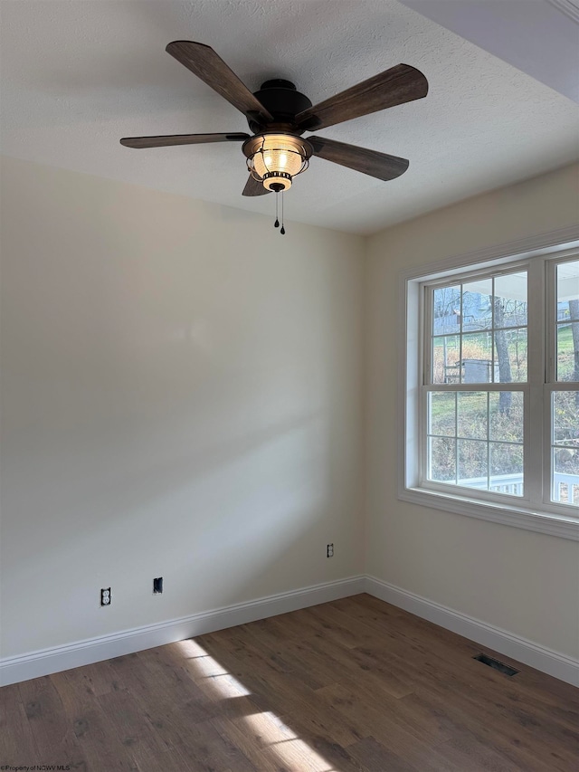 unfurnished room featuring a textured ceiling, ceiling fan, and dark wood-type flooring