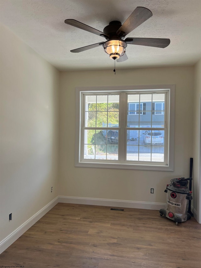 spare room featuring ceiling fan, wood-type flooring, and a textured ceiling