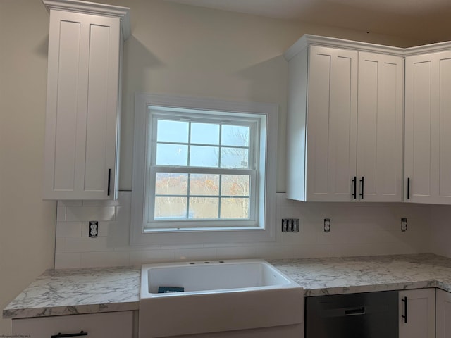 kitchen featuring white cabinets, light stone counters, stainless steel dishwasher, and backsplash