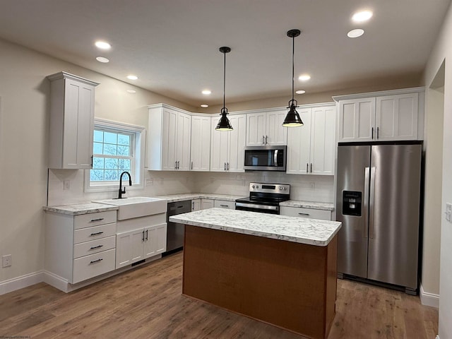 kitchen with pendant lighting, white cabinets, sink, a kitchen island, and stainless steel appliances