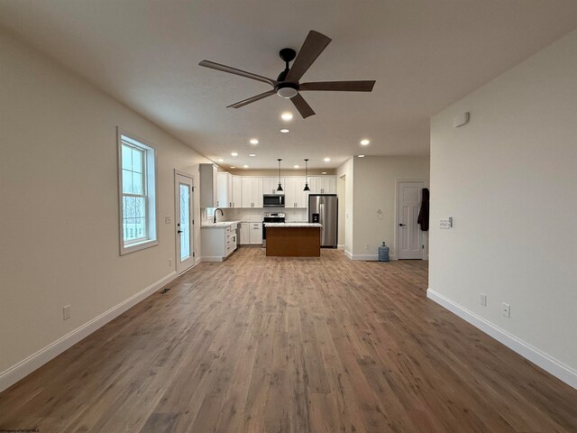 unfurnished living room with ceiling fan, hardwood / wood-style floors, and sink