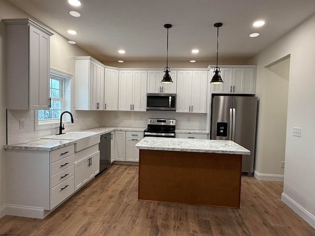 kitchen with sink, a center island, pendant lighting, appliances with stainless steel finishes, and hardwood / wood-style flooring