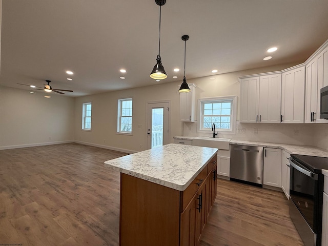 kitchen featuring appliances with stainless steel finishes, sink, white cabinets, dark hardwood / wood-style floors, and a kitchen island