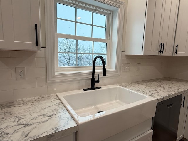 room details with light stone counters, white cabinetry, sink, and tasteful backsplash