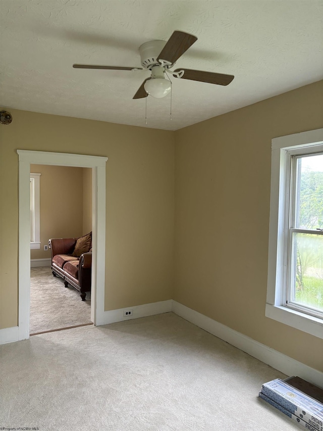 spare room featuring light carpet, a textured ceiling, and ceiling fan