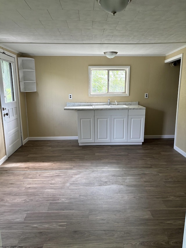 kitchen with white cabinets, wood walls, sink, and dark wood-type flooring