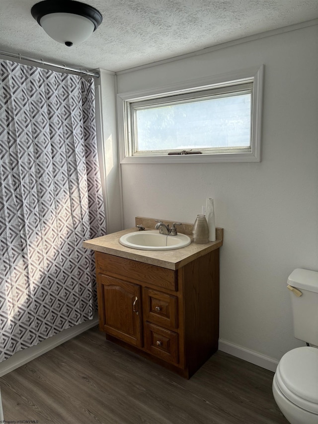 bathroom featuring wood-type flooring, vanity, a textured ceiling, and toilet