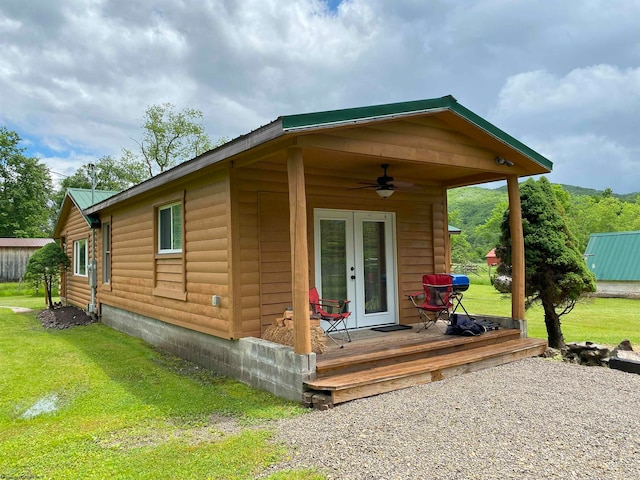 rear view of property with a lawn, ceiling fan, a wooden deck, and french doors