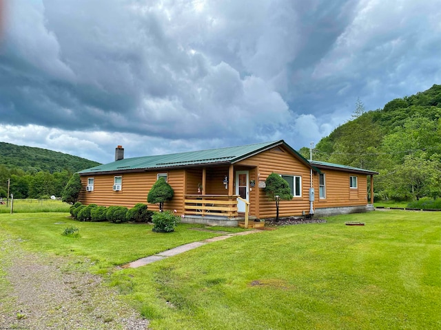 log home with covered porch and a front lawn