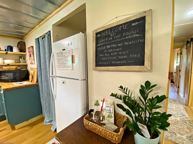 kitchen with butcher block counters, white refrigerator, a barn door, and light hardwood / wood-style floors