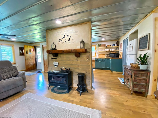 living room with light hardwood / wood-style floors, a wood stove, and wooden walls