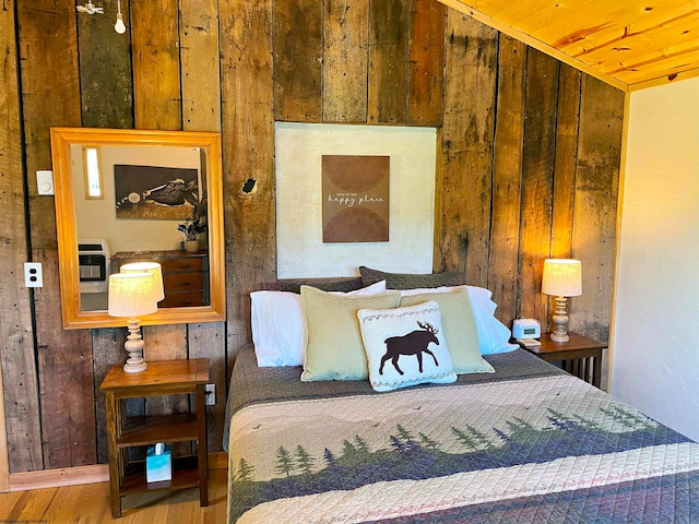 bedroom with heating unit, wood walls, wooden ceiling, and hardwood / wood-style flooring