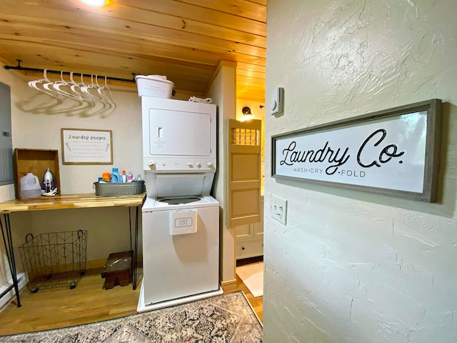 laundry area featuring wooden ceiling, stacked washing maching and dryer, a baseboard radiator, and hardwood / wood-style flooring