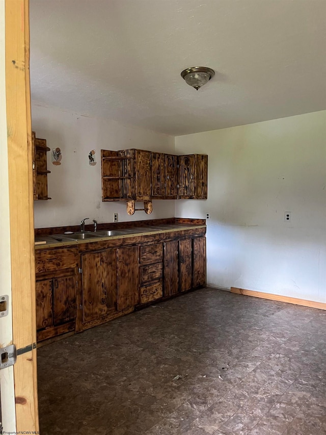 kitchen with sink, dark tile flooring, and dark brown cabinetry