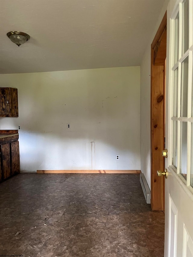 spare room with a baseboard heating unit and dark tile floors