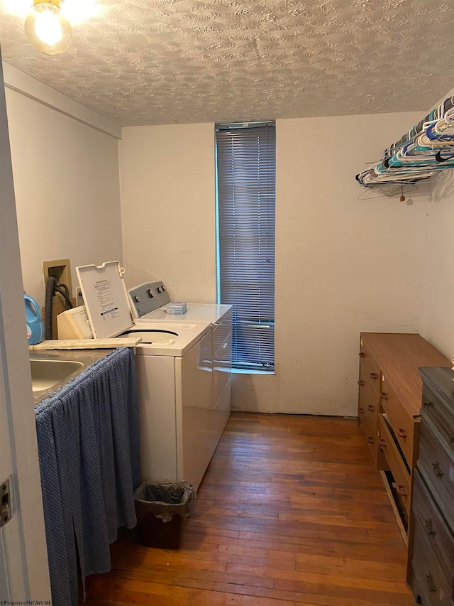 laundry area with a textured ceiling, separate washer and dryer, and dark hardwood / wood-style flooring