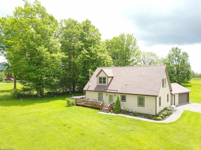 rear view of property featuring a deck, a garage, and a lawn