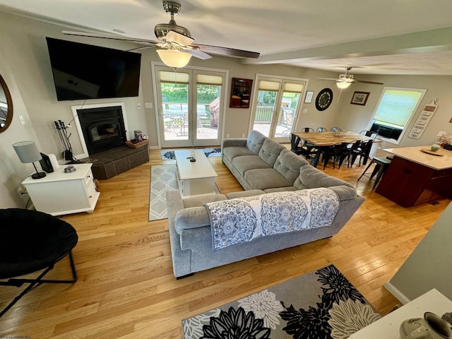 living room featuring ceiling fan, a fireplace, and light wood-type flooring