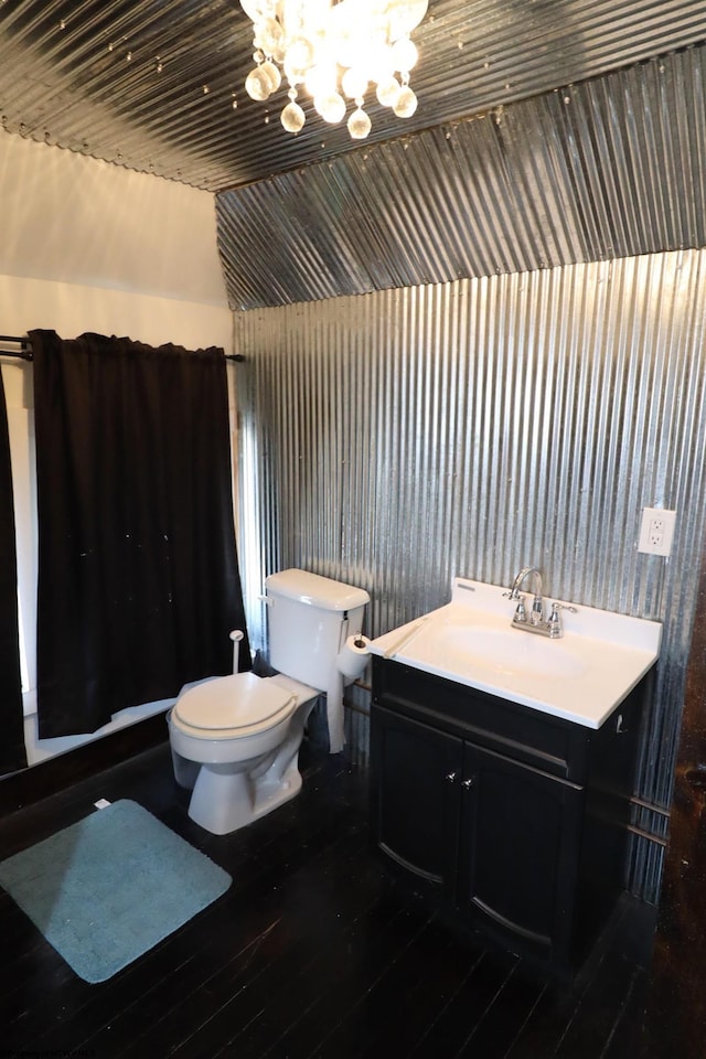 bathroom featuring a chandelier, vanity, toilet, and vaulted ceiling