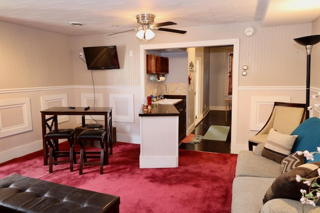 living room featuring carpet flooring, ceiling fan, and sink