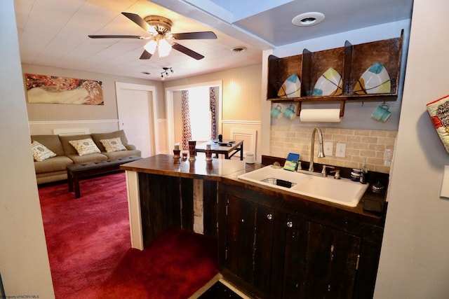 kitchen featuring backsplash, sink, ceiling fan, dark brown cabinets, and carpet floors